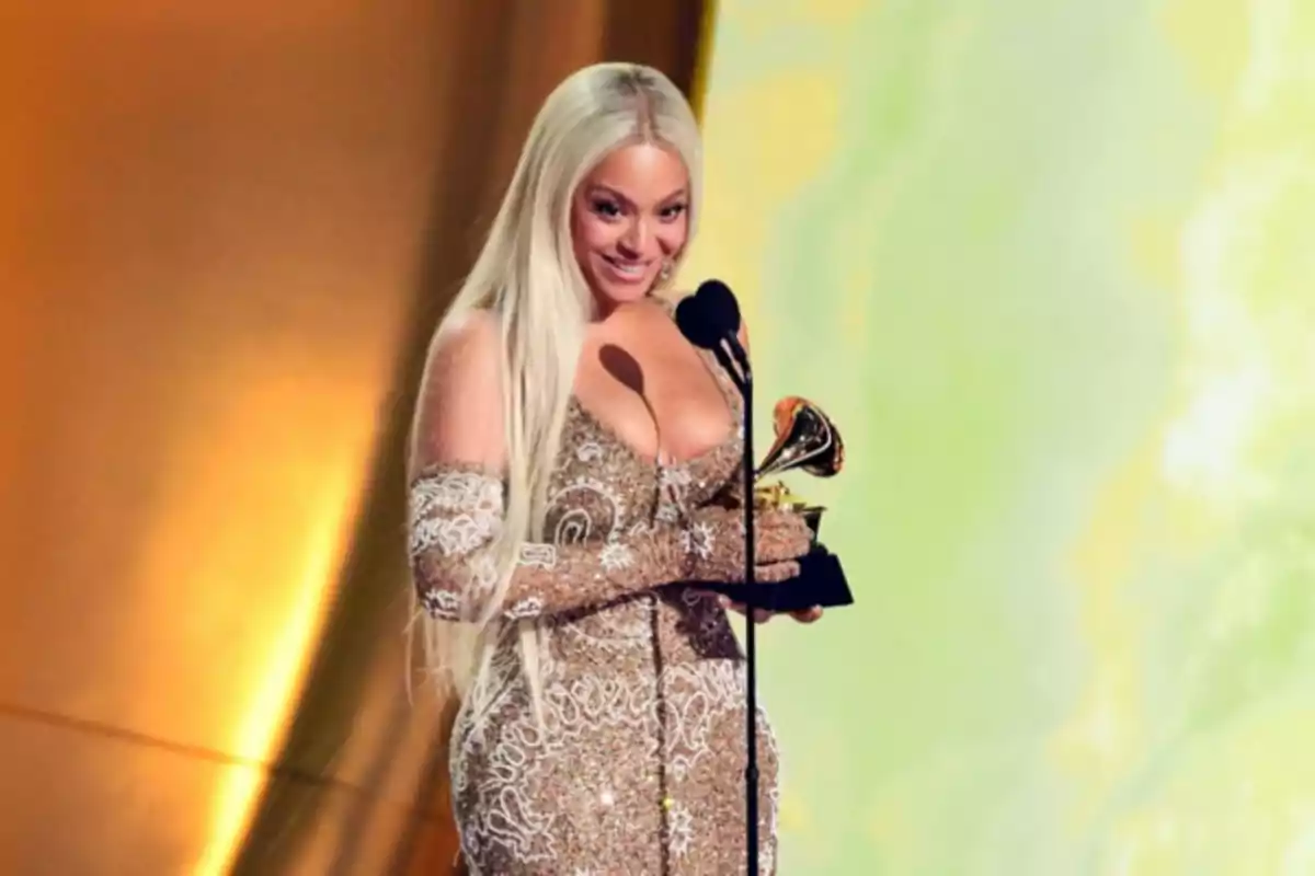 Una persona con un vestido brillante sostiene un premio Grammy mientras habla en un micrófono.