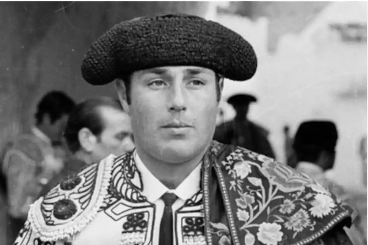 Un torero con traje tradicional y montera en una plaza de toros.
