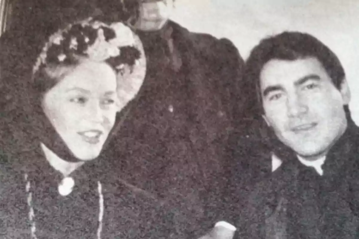 Una mujer y un hombre vestidos con ropa de época posan juntos para una fotografía en blanco y negro. Una mujer y un hombre vestidos con ropa de época posan juntos para una fotografía en blanco y negro.