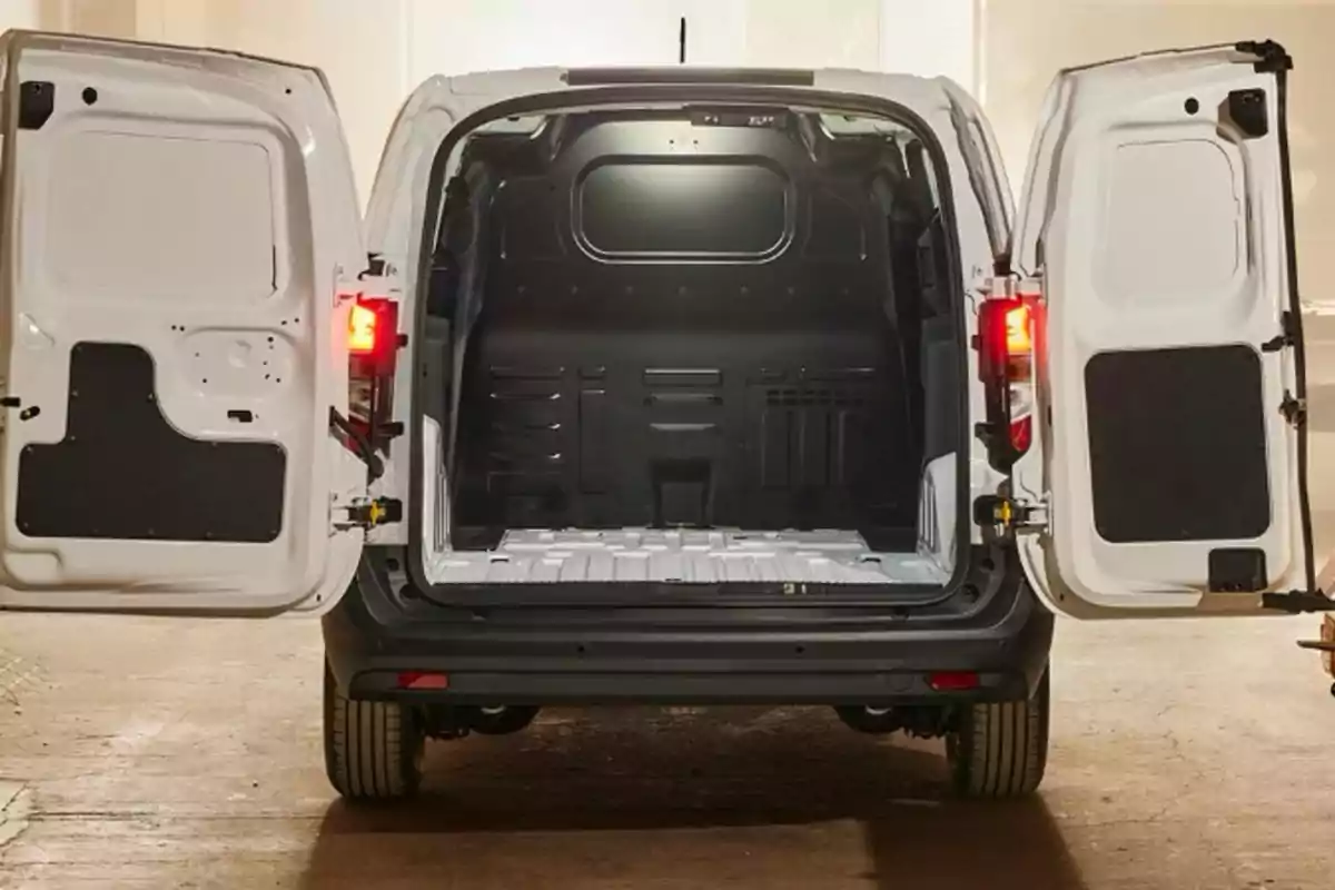 La imagen muestra la parte trasera de una furgoneta blanca con las puertas abiertas, revelando un espacio de carga vacío y bien iluminado. La imagen muestra la parte trasera de una furgoneta blanca con las puertas abiertas, revelando un espacio de carga vacío y bien iluminado.