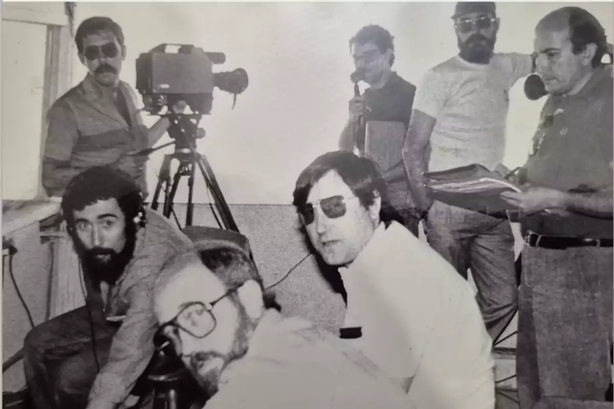 Un grupo de hombres en un estudio de grabación con equipo de filmación y documentos. Un grupo de hombres en un estudio de grabación con equipo de filmación y documentos.