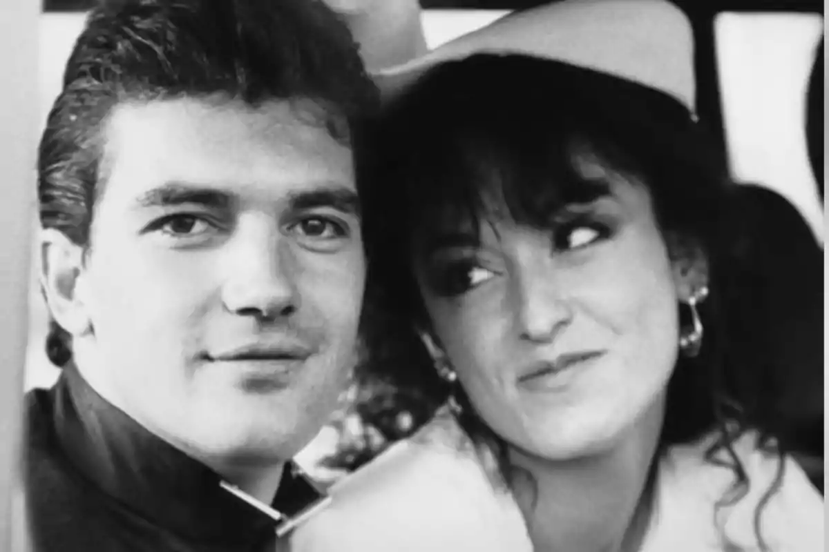 Una pareja joven sonríe mientras posa para una foto en blanco y negro. Una pareja joven sonríe mientras posa para una foto en blanco y negro.