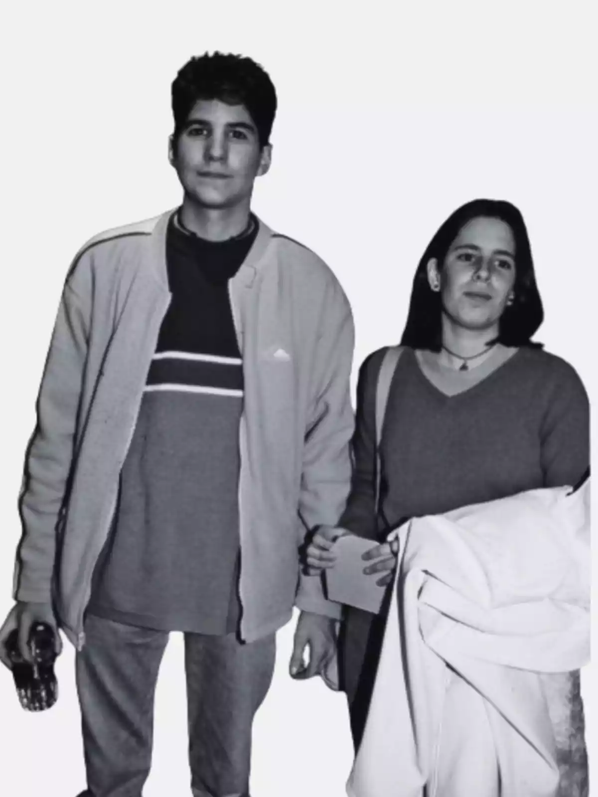 Dos personas posando juntas, una sosteniendo una botella y la otra un abrigo.