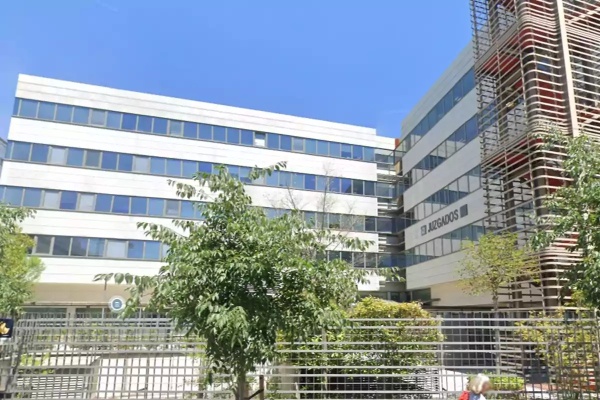 Edificio moderno de oficinas con ventanas grandes y árboles en el frente.