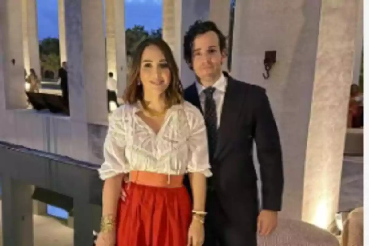Una pareja posando en un elegante entorno arquitectónico con columnas iluminadas. Una pareja posando en un elegante entorno arquitectónico con columnas iluminadas.