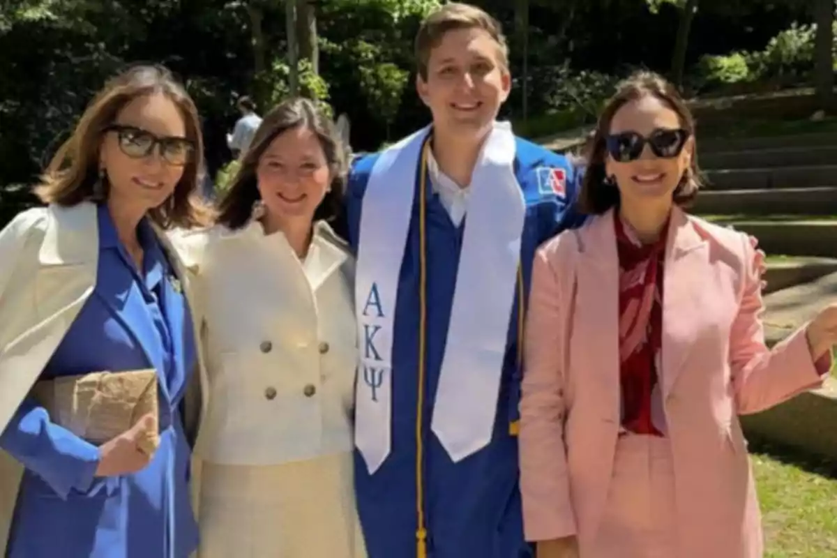 Un grupo de personas posando al aire libre, una de ellas lleva una toga de graduación azul con una estola blanca. Un grupo de personas posando al aire libre, una de ellas lleva una toga de graduación azul con una estola blanca.