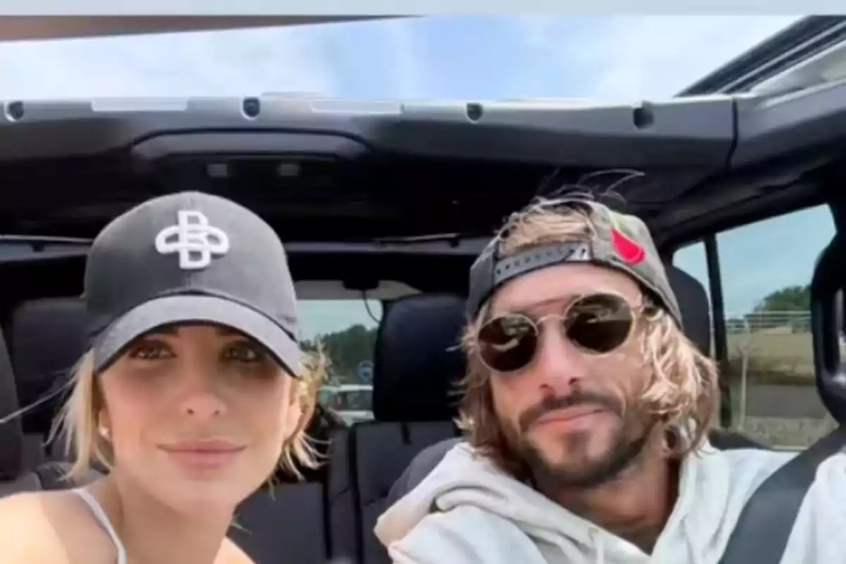 Pareja joven sentada en un auto descapotable ambos usando gorras y el hombre lleva gafas de sol Pareja joven sentada en un auto descapotable ambos usando gorras y el hombre lleva gafas de sol