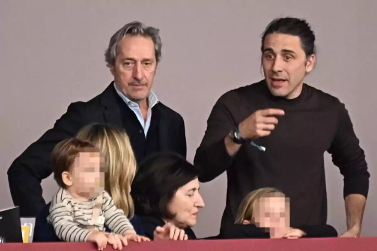 A group of adults and children with the children's faces pixelated are looking at something outside the frame while one of the men points forward. A group of adults and children with the children's faces pixelated are looking at something outside the frame while one of the men points forward.