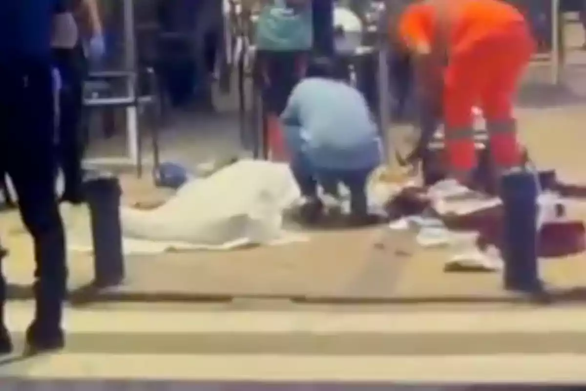 Varias personas atienden una emergencia en la vía pública junto a un cuerpo cubierto con una sábana blanca