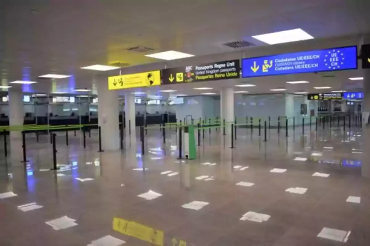 Zona de control de pasaportes en un aeropuerto con letreros de señalización y filas vacías Zona de control de pasaportes en un aeropuerto con letreros de señalización y filas vacías