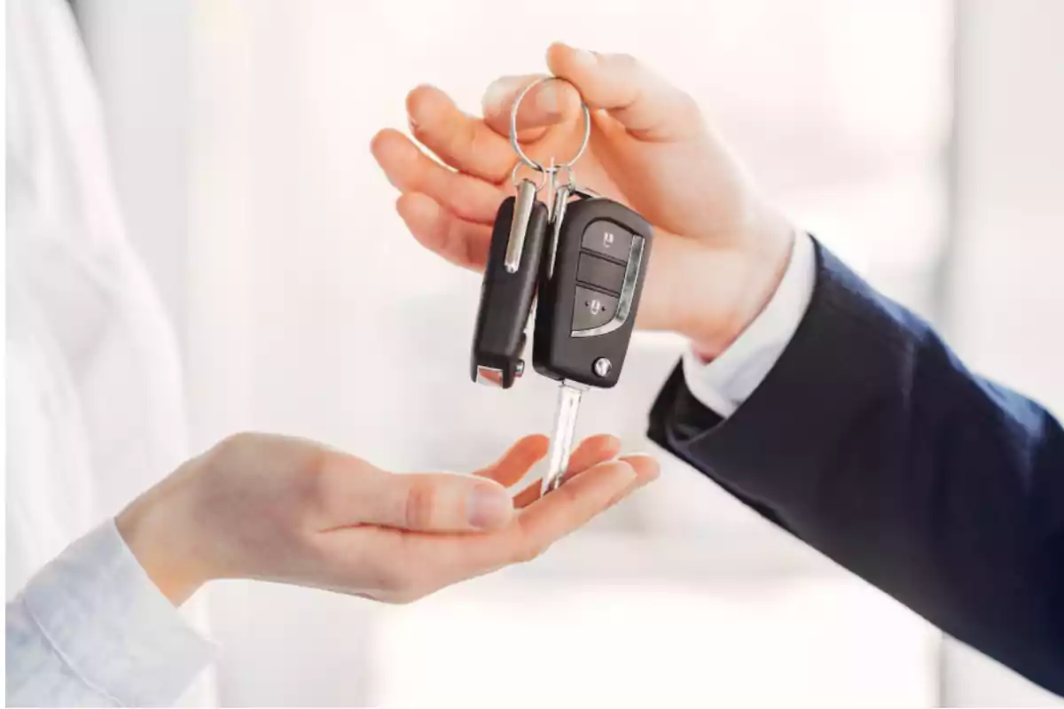 Una persona entrega unas llaves de coche a otra persona que extiende la mano para recibirlas