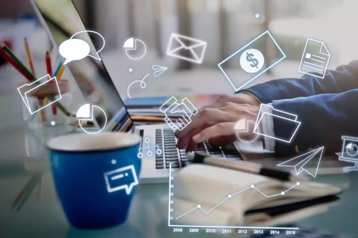 Persona usando una laptop con gráficos y símbolos digitales flotando, taza azul y útiles de oficina sobre el escritorio