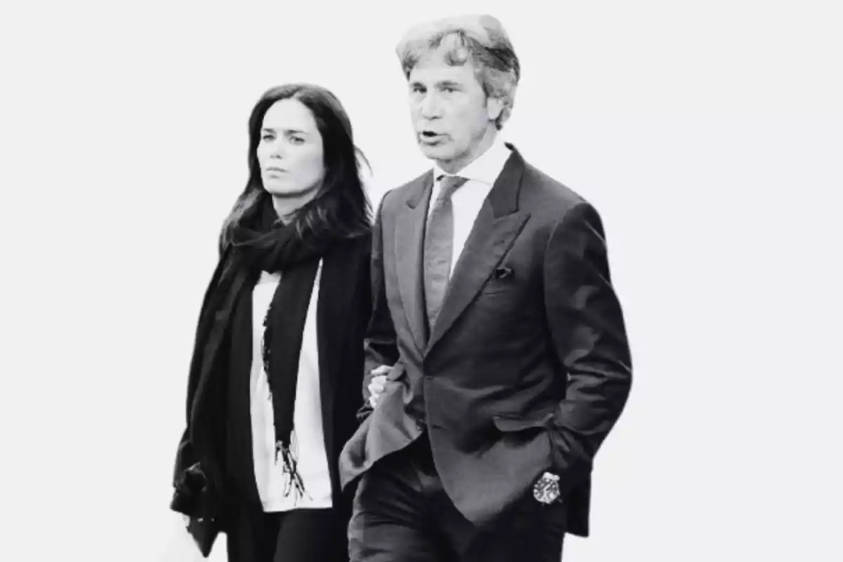 Pareja caminando juntos con expresión seria ambos vestidos de manera formal en una imagen en blanco y negro Pareja caminando juntos con expresión seria ambos vestidos de manera formal en una imagen en blanco y negro