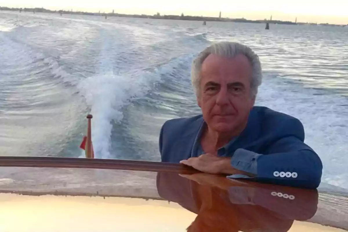 Hombre de cabello canoso con saco azul viajando en un bote sobre el mar al atardecer Hombre de cabello canoso con saco azul viajando en un bote sobre el mar al atardecer