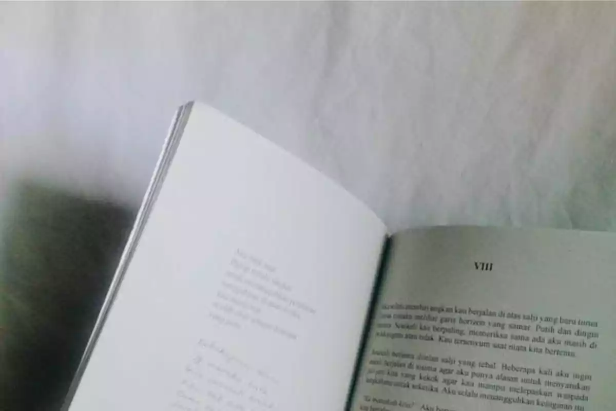 Libro abierto sobre una superficie blanca mostrando páginas con texto en diferentes idiomas.