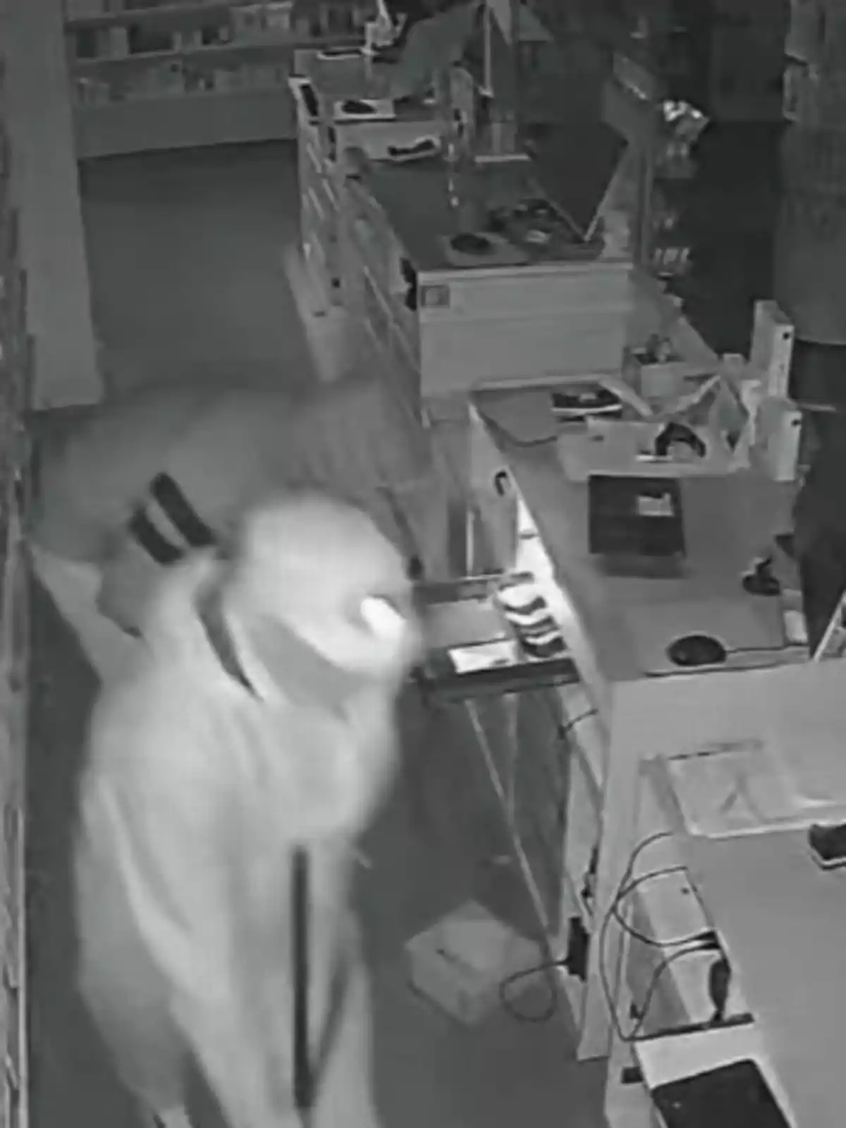 Dos personas encapuchadas dentro de una tienda durante la noche, captadas por una cámara de seguridad mientras revisan el área de la caja registradora. Dos personas encapuchadas dentro de una tienda durante la noche, captadas por una cámara de seguridad mientras revisan el área de la caja registradora.