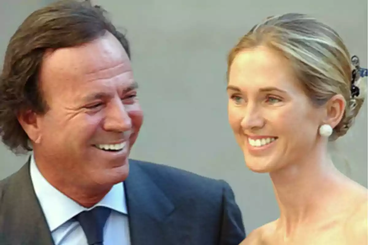 Un hombre y una mujer sonríen elegantemente vestidos en un evento formal