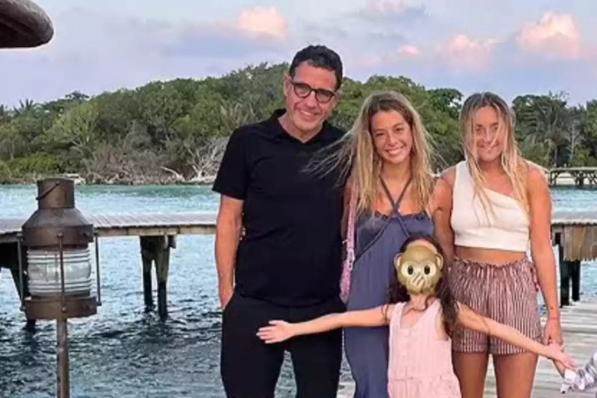 Familia posando sonriente frente a un muelle de madera con agua y vegetación al fondo mientras una niña pequeña con máscara de mono extiende los brazos al frente Familia posando sonriente frente a un muelle de madera con agua y vegetación al fondo mientras una niña pequeña con máscara de mono extiende los brazos al frente