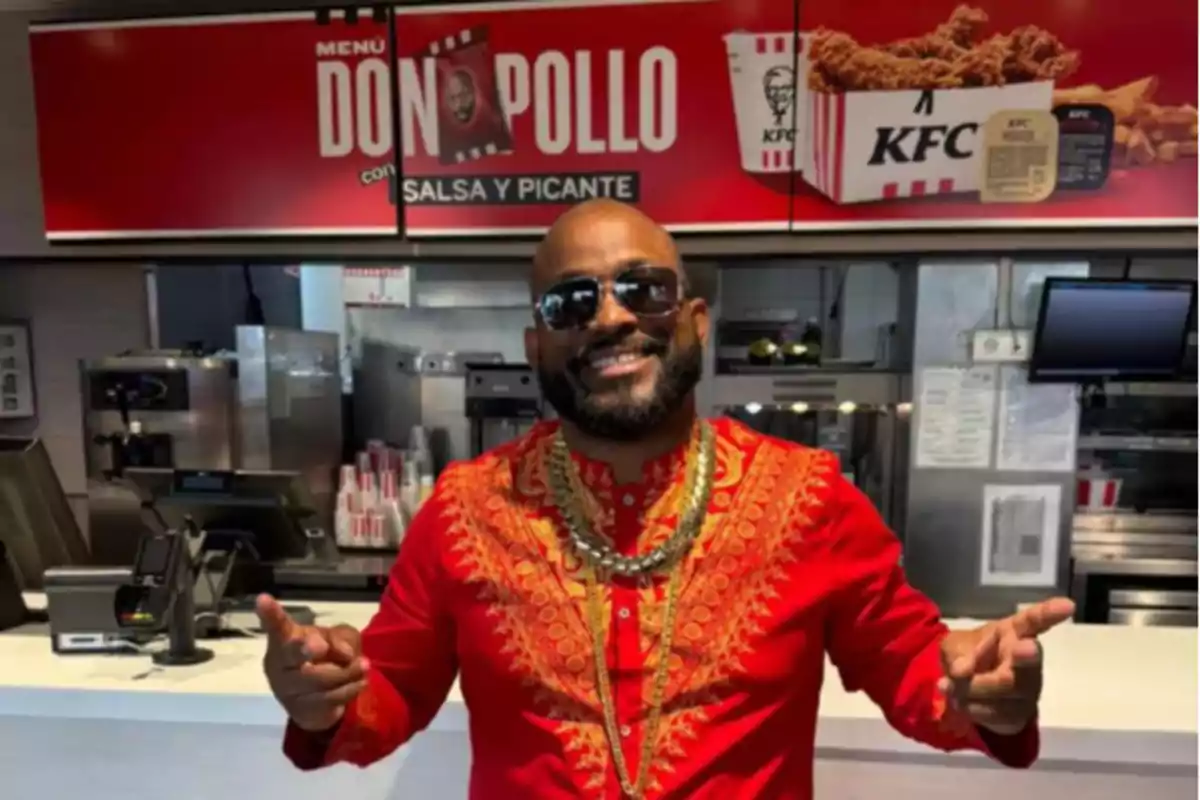 Hombre sonriente con gafas de sol y camisa roja decorada posando en un restaurante de comida rápida KFC Hombre sonriente con gafas de sol y camisa roja decorada posando en un restaurante de comida rápida KFC
