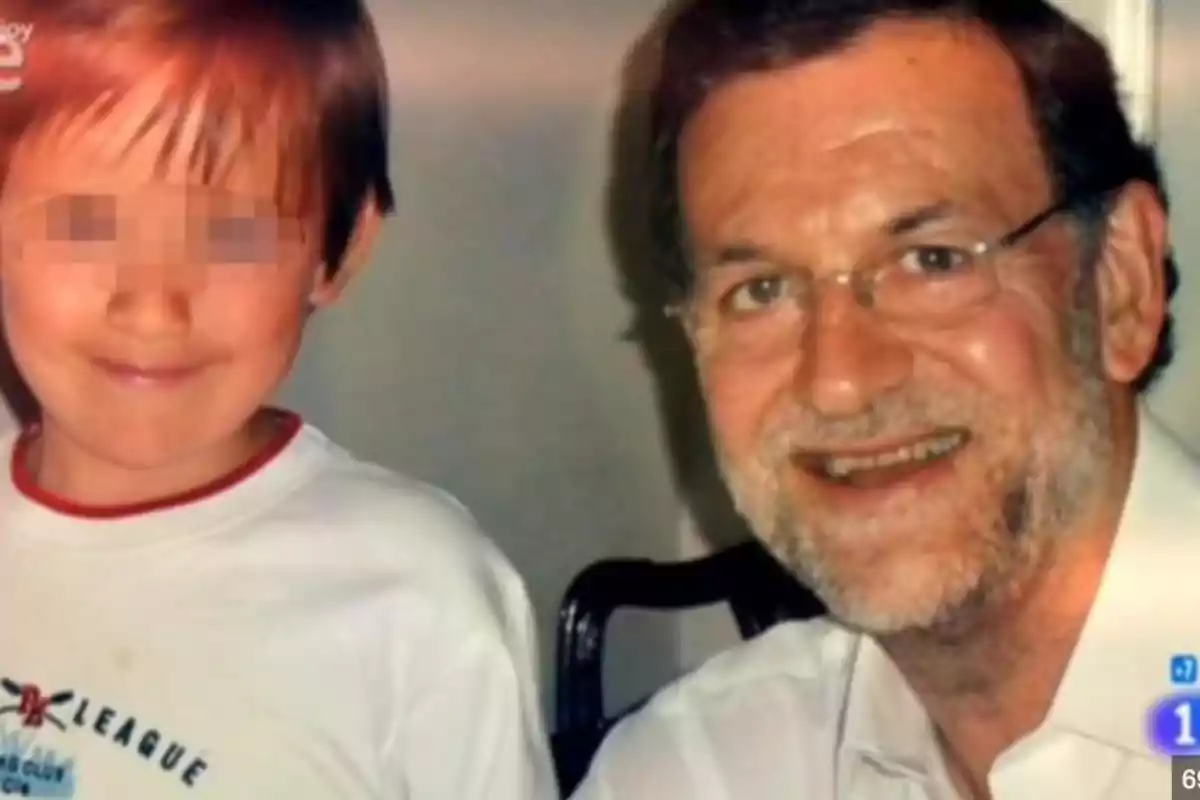 Un hombre adulto con gafas y barba sonríe junto a un niño cuyo rostro está pixelado Un hombre adulto con gafas y barba sonríe junto a un niño cuyo rostro está pixelado