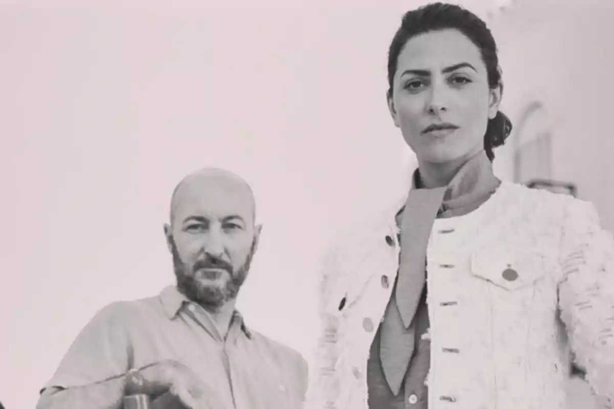Fotografía en blanco y negro de una mujer y un hombre mirando a la cámara con expresiones serias Fotografía en blanco y negro de una mujer y un hombre mirando a la cámara con expresiones serias