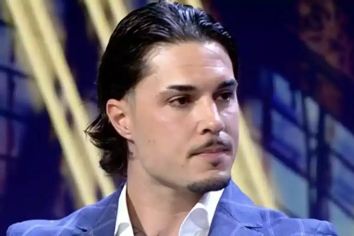 Carlo Costanzia con cabello oscuro y peinado hacia atrás, vistiendo un traje azul, en un entorno de estudio de televisión en De Viernes. Carlo Costanzia con cabello oscuro y peinado hacia atrás, vistiendo un traje azul, en un entorno de estudio de televisión en De Viernes.