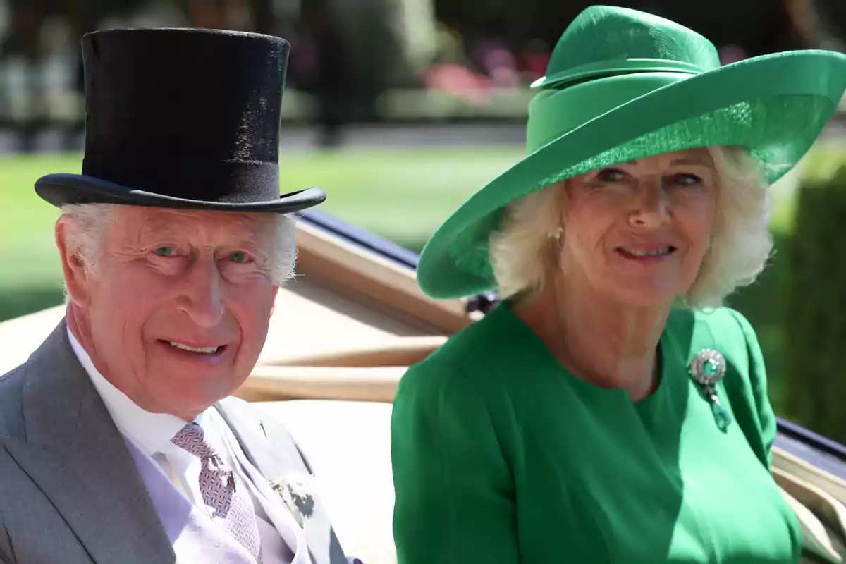 Carlos III con sombrero de copa negro y la reina Camila con sombrero verde posan sonrientes vestidos de manera elegante en un evento al aire libre Carlos III con sombrero de copa negro y la reina Camila con sombrero verde posan sonrientes vestidos de manera elegante en un evento al aire libre
