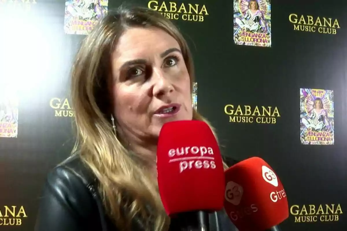 Carlota Corredera siendo entrevistada frente a un fondo del Gabana Music Club con micrófonos de prensa.