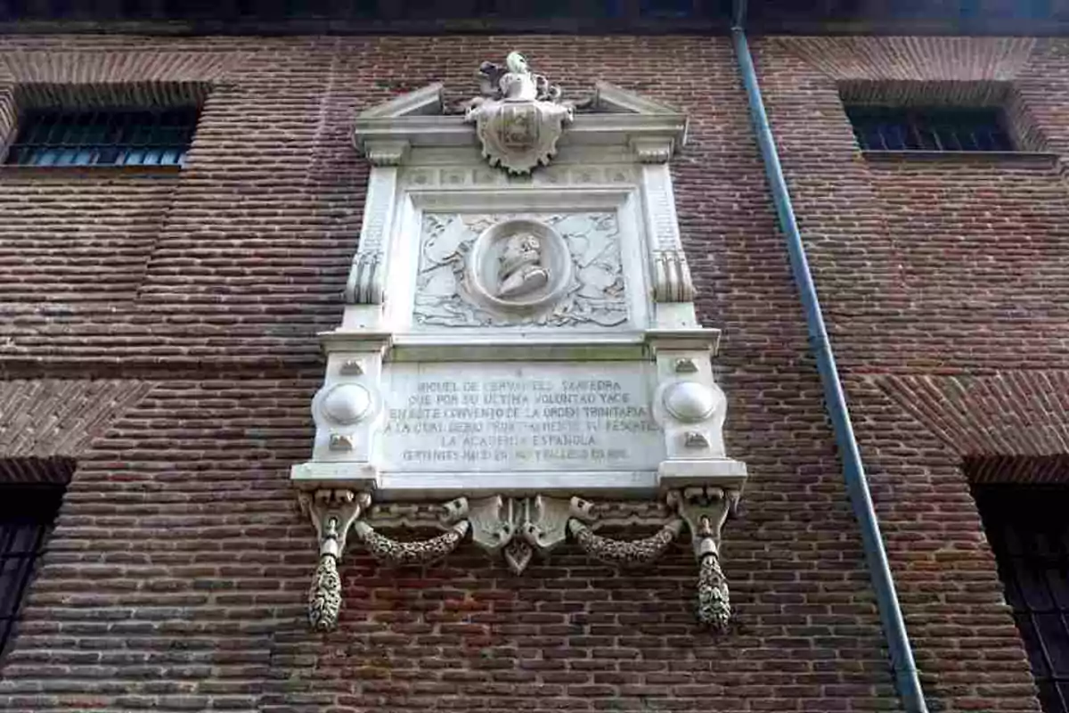 Placa conmemorativa de Miguel de Cervantes Saavedra en una pared de ladrillo.