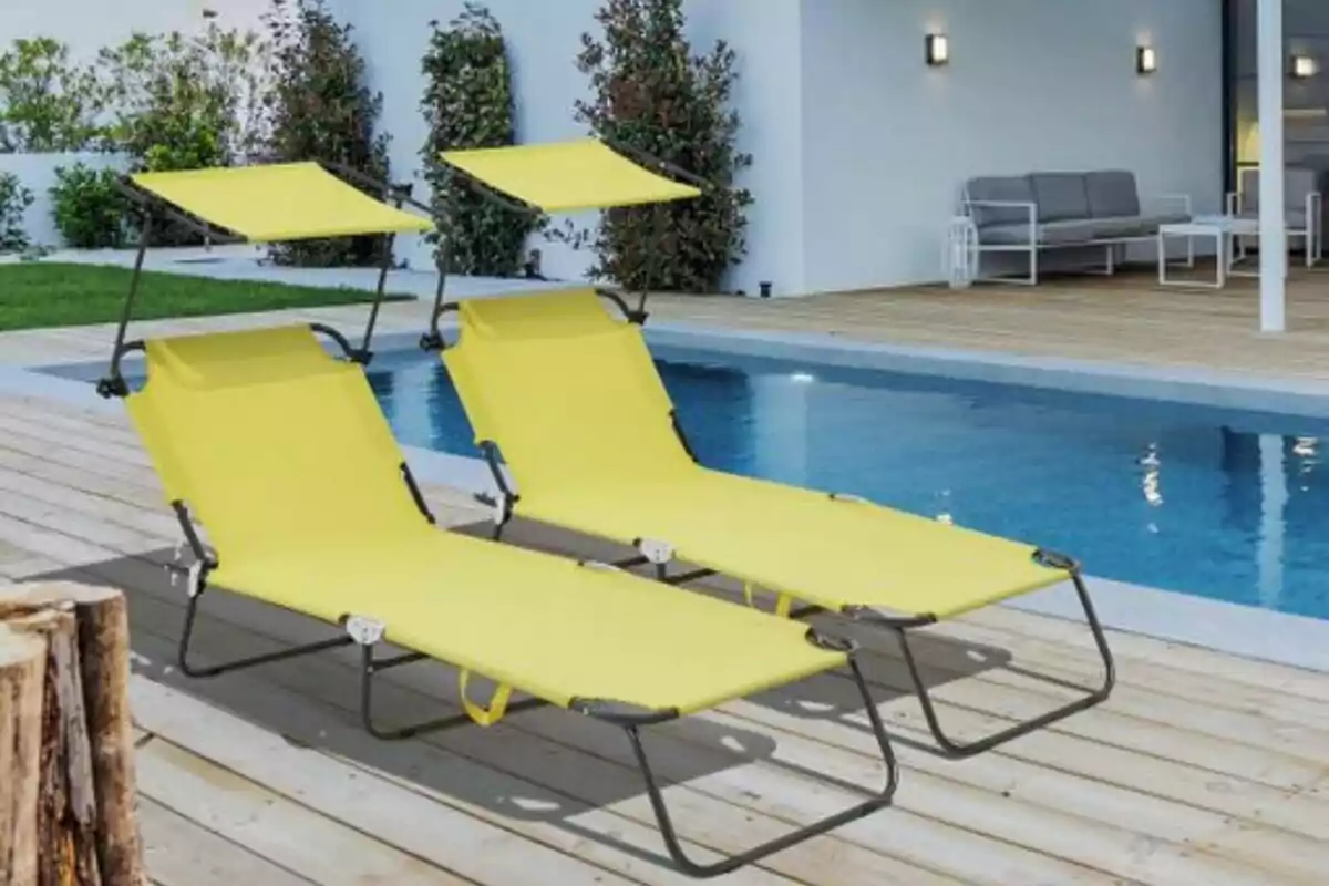 Dos tumbonas amarillas con toldo junto a una piscina en una terraza de madera Dos tumbonas amarillas con toldo junto a una piscina en una terraza de madera