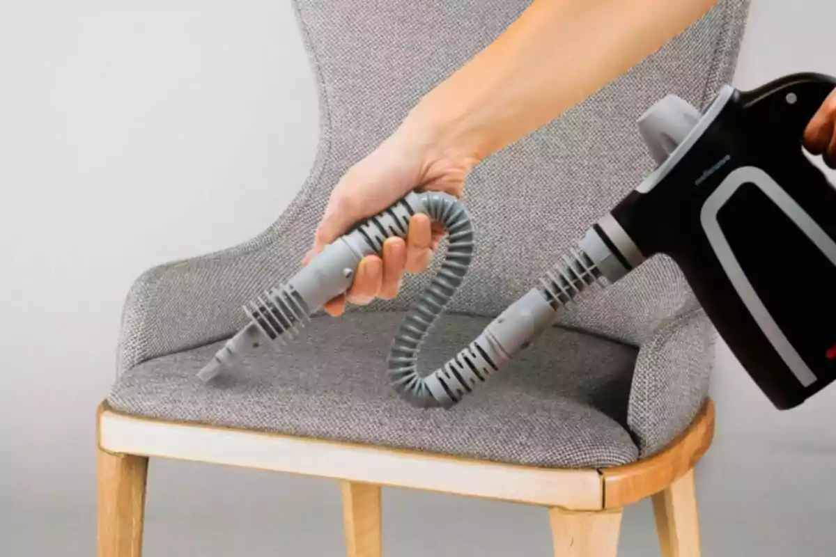 Persona usando un limpiador a vapor en una silla tapizada. Persona usando un limpiador a vapor en una silla tapizada.