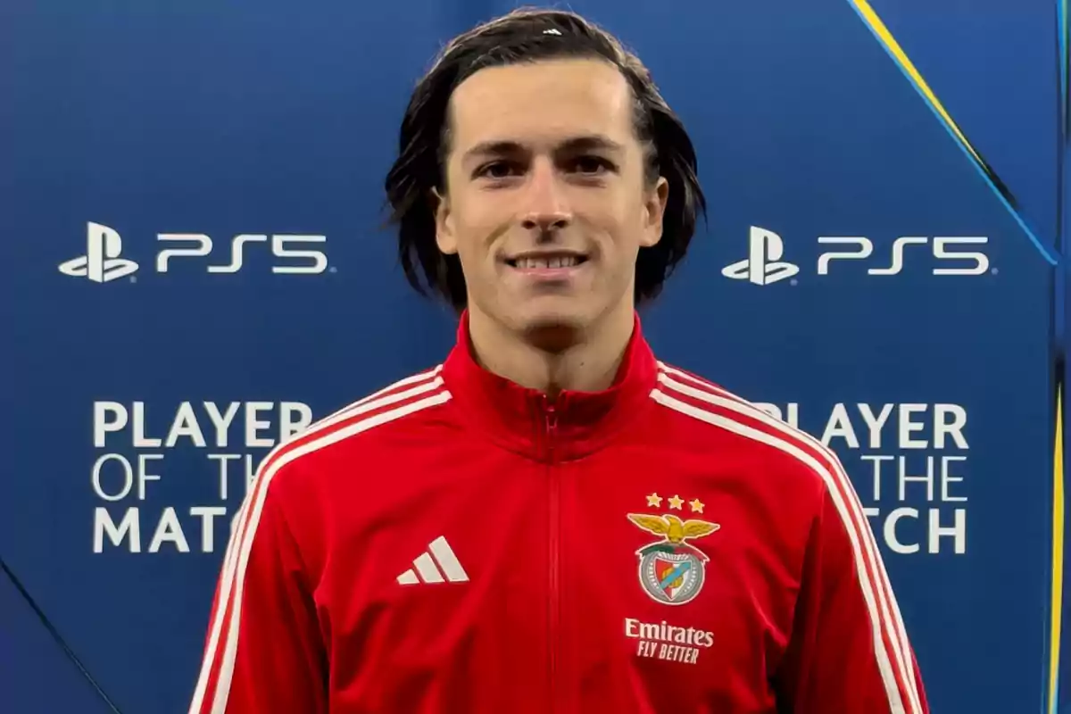 Jugador del Benfica con chaqueta roja posando frente a un fondo azul con logotipos de PlayStation y el texto Player of the Match Jugador del Benfica con chaqueta roja posando frente a un fondo azul con logotipos de PlayStation y el texto Player of the Match