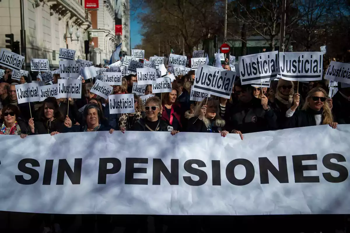 Un grupo de personas participa en una manifestación sosteniendo pancartas que dicen 