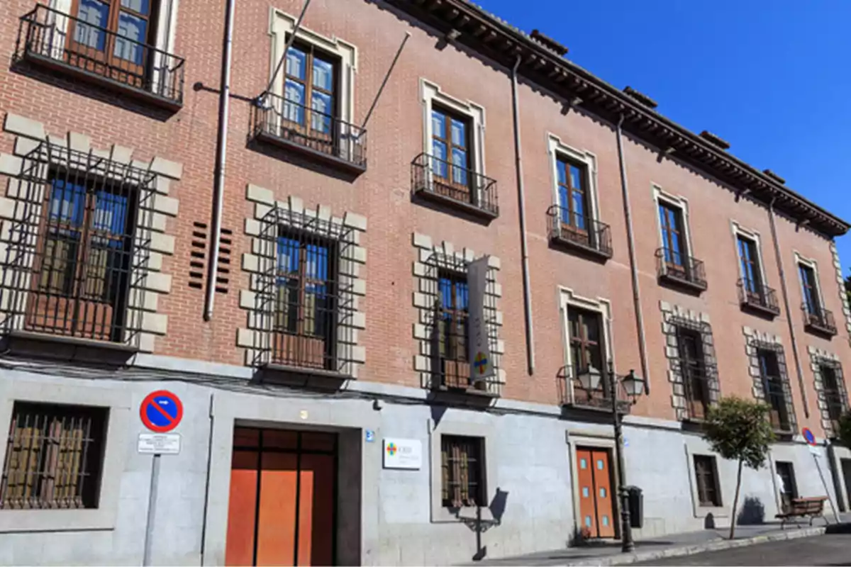 Fachada de un edificio de ladrillo con ventanas enrejadas y puertas de madera.