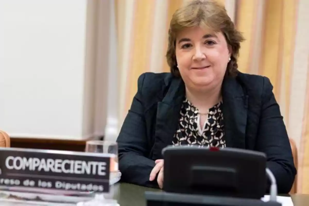 Una mujer sentada en una mesa con un cartel que dice 