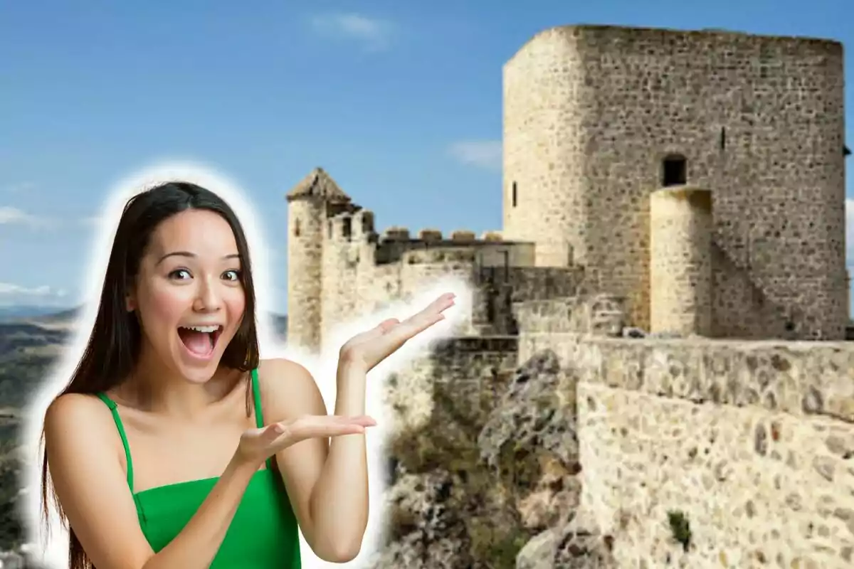 Mujer sonriente con vestido verde señalando un castillo de piedra de Olvera (Cádiz) en un día soleado.