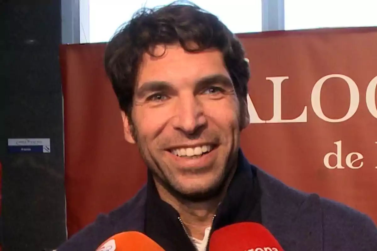 Cayetano Rivera sonriente frente a un fondo rojo con micrófonos en primer plano. Cayetano Rivera sonriente frente a un fondo rojo con micrófonos en primer plano.