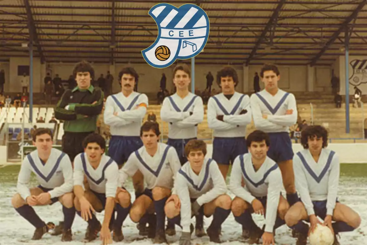 Equipo de fútbol posando en el campo con uniforme blanco y azul y un escudo del club en la parte superior.