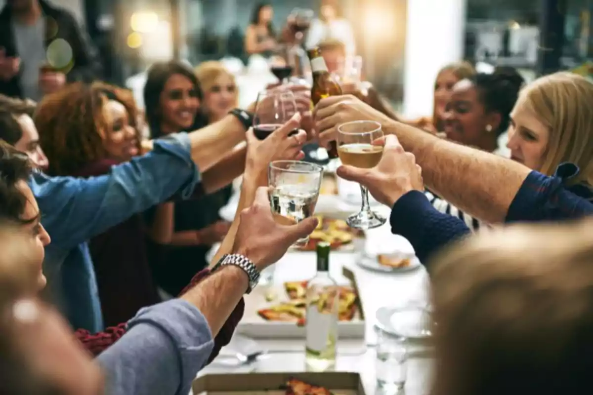 Un grupo de personas brindando con copas y botellas en una reunión social.