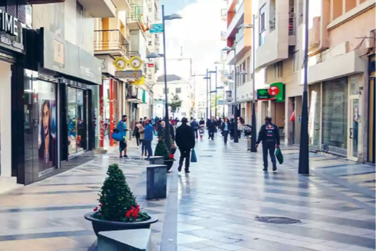 Una calle peatonal con personas caminando y tiendas a los lados.