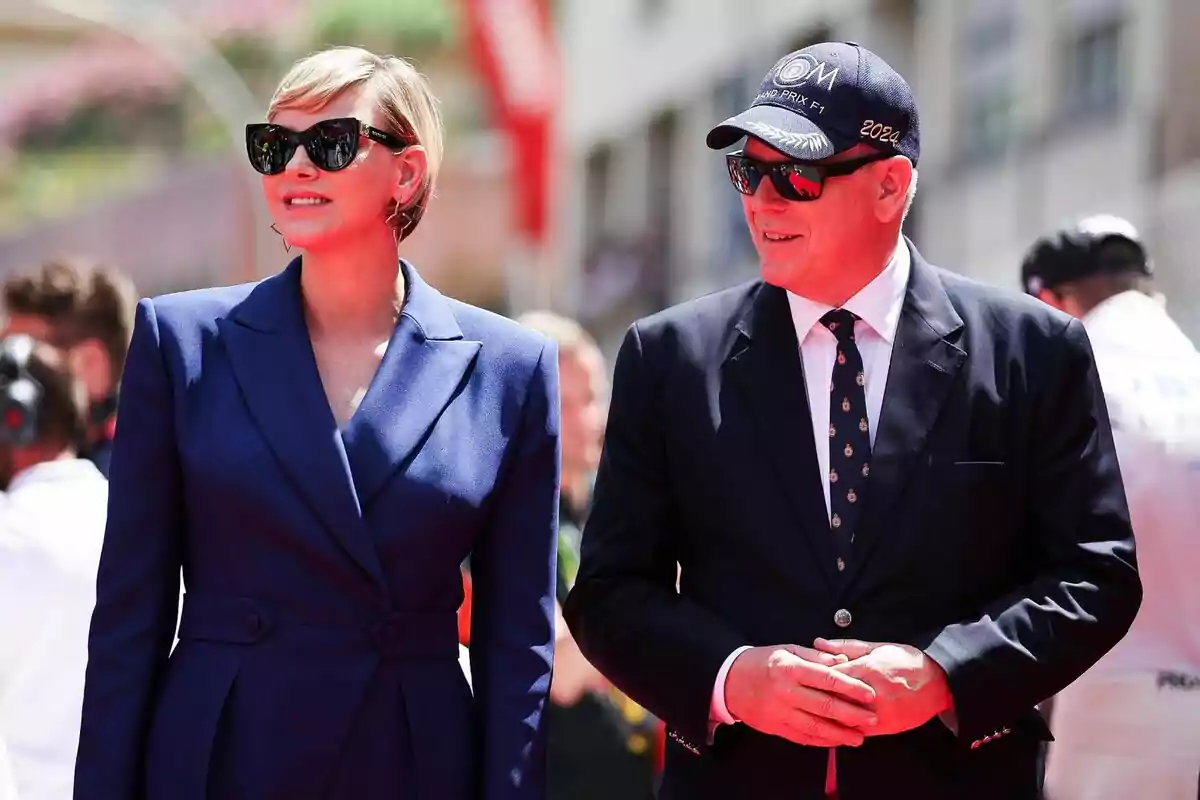 Charlene sonriendo con gafas de sol y traje azul junto a Alberto de Mónaco sonriendo con gorra y traje azules y las manos juntas mientras miran a un lado Charlene sonriendo con gafas de sol y traje azul junto a Alberto de Mónaco sonriendo con gorra y traje azules y las manos juntas mientras miran a un lado