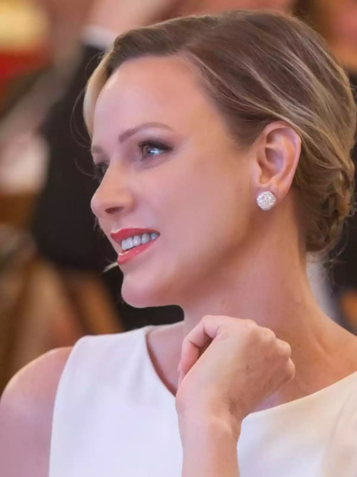 Una persona sonriendo elegantemente con un vestido blanco y aretes brillantes. Una persona sonriendo elegantemente con un vestido blanco y aretes brillantes.