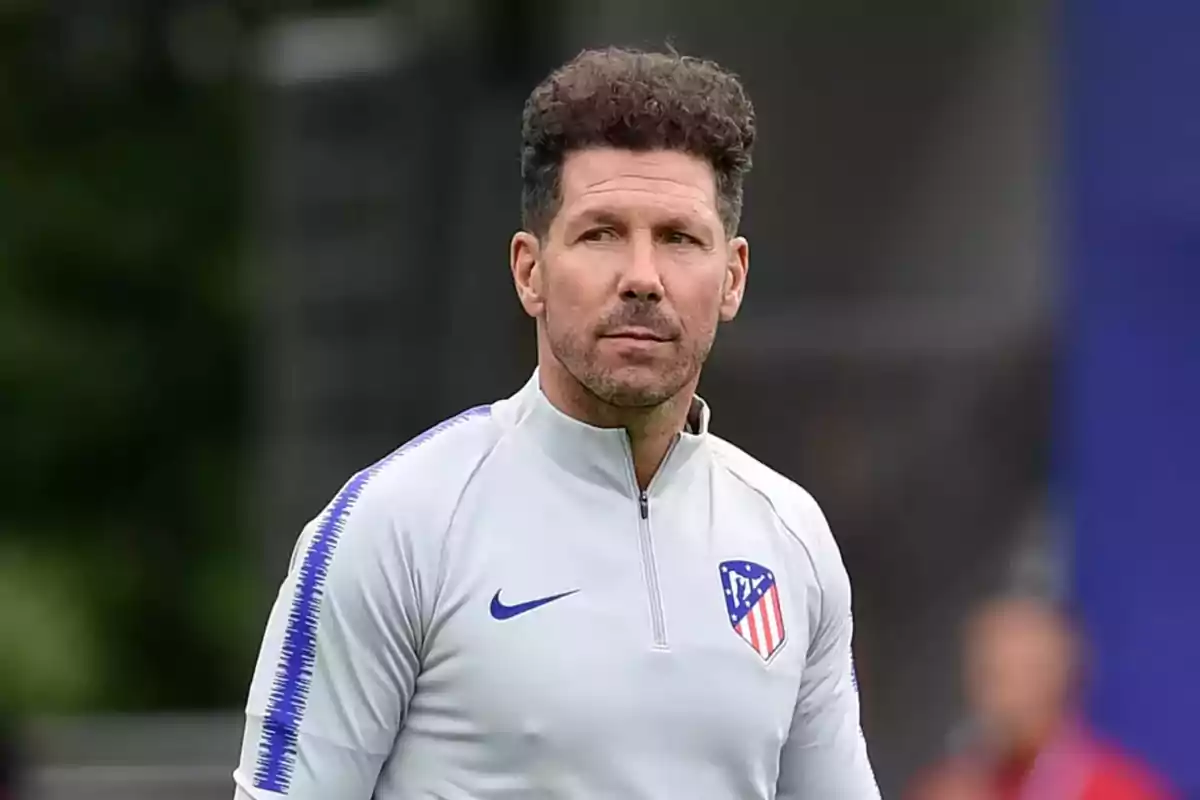 Hombre con chaqueta deportiva gris con el logo del Atlético de Madrid.