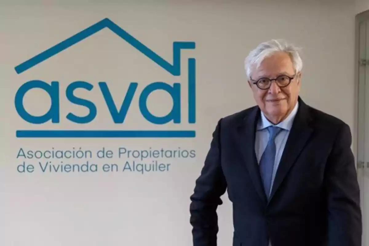 Un hombre de traje y corbata está de pie junto a un logotipo azul de una asociación de propietarios de vivienda en alquiler.