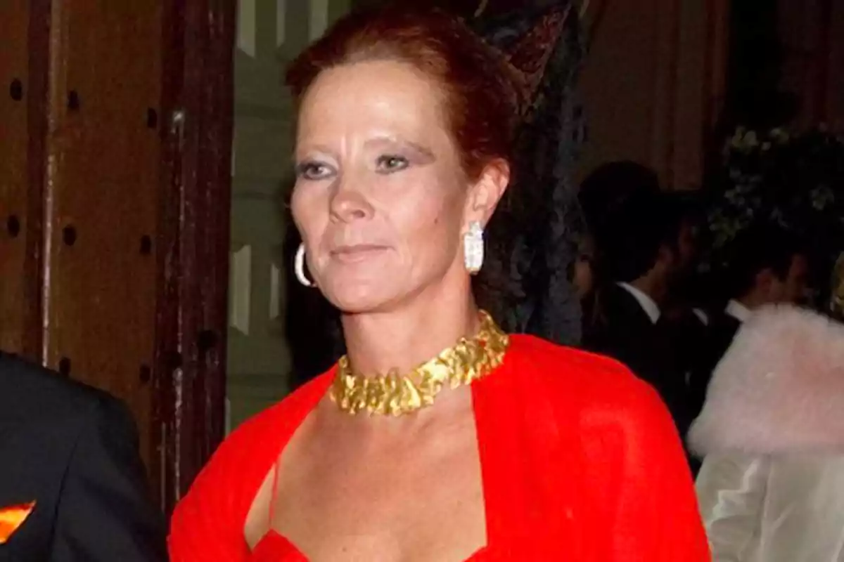 Mujer con vestido rojo y collar dorado en un evento formal.