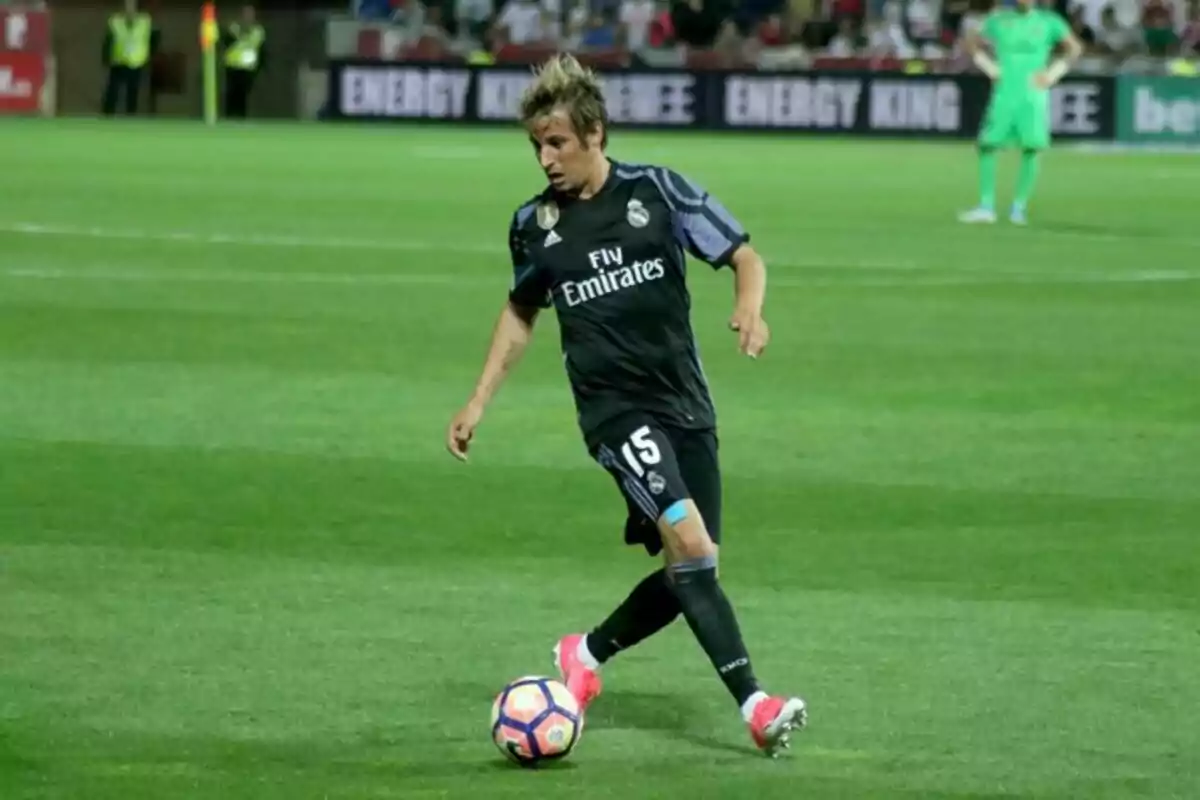 Futbolista del Real Madrid con uniforme negro controlando el balón en un partido sobre césped