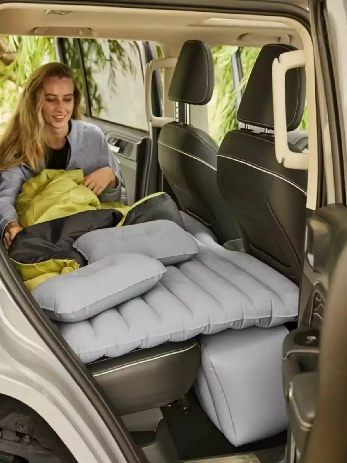 Una persona acomodando un colchón inflable de Lidl en el asiento trasero de un automóvil. Una persona acomodando un colchón inflable de Lidl en el asiento trasero de un automóvil.