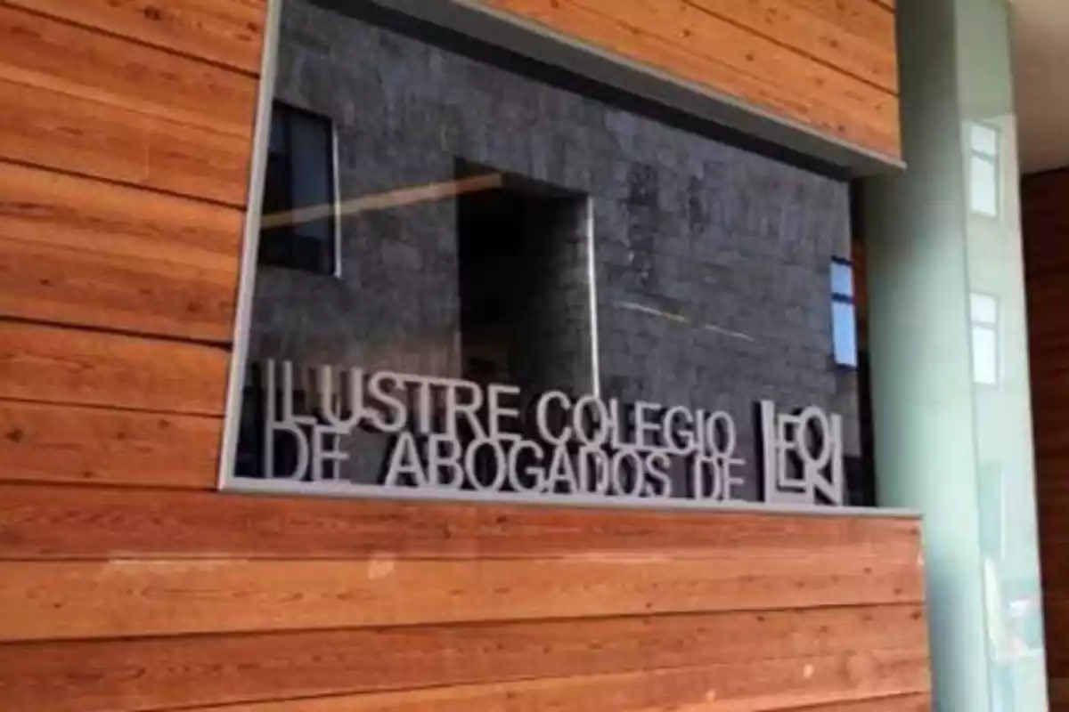 Cartel del Ilustre Colegio de Abogados de León colocado en un marco sobre una pared de madera.