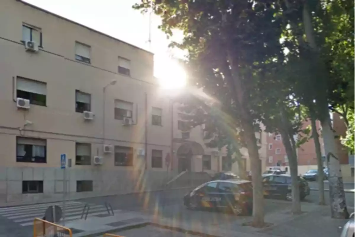 Edificio con coches de policía estacionados y árboles al frente iluminados por el sol. Edificio con coches de policía estacionados y árboles al frente iluminados por el sol.