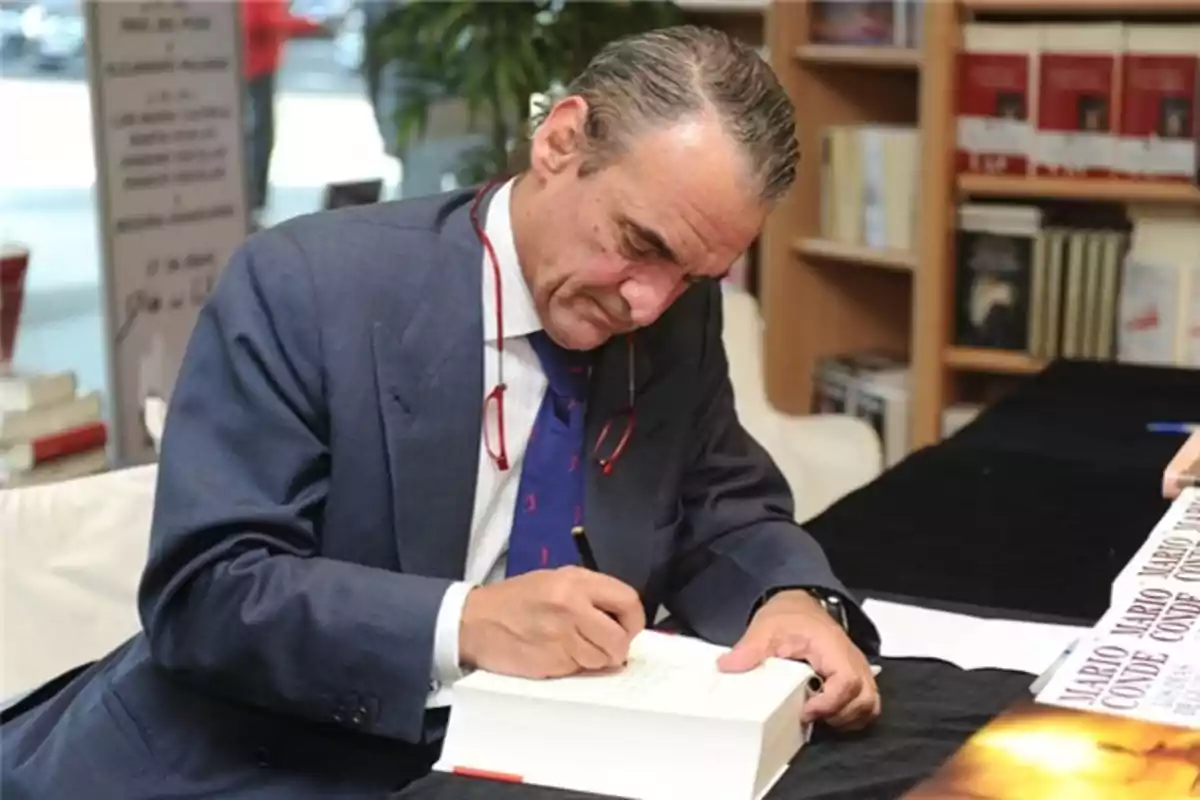 Un hombre de traje firmando un libro en una librería.